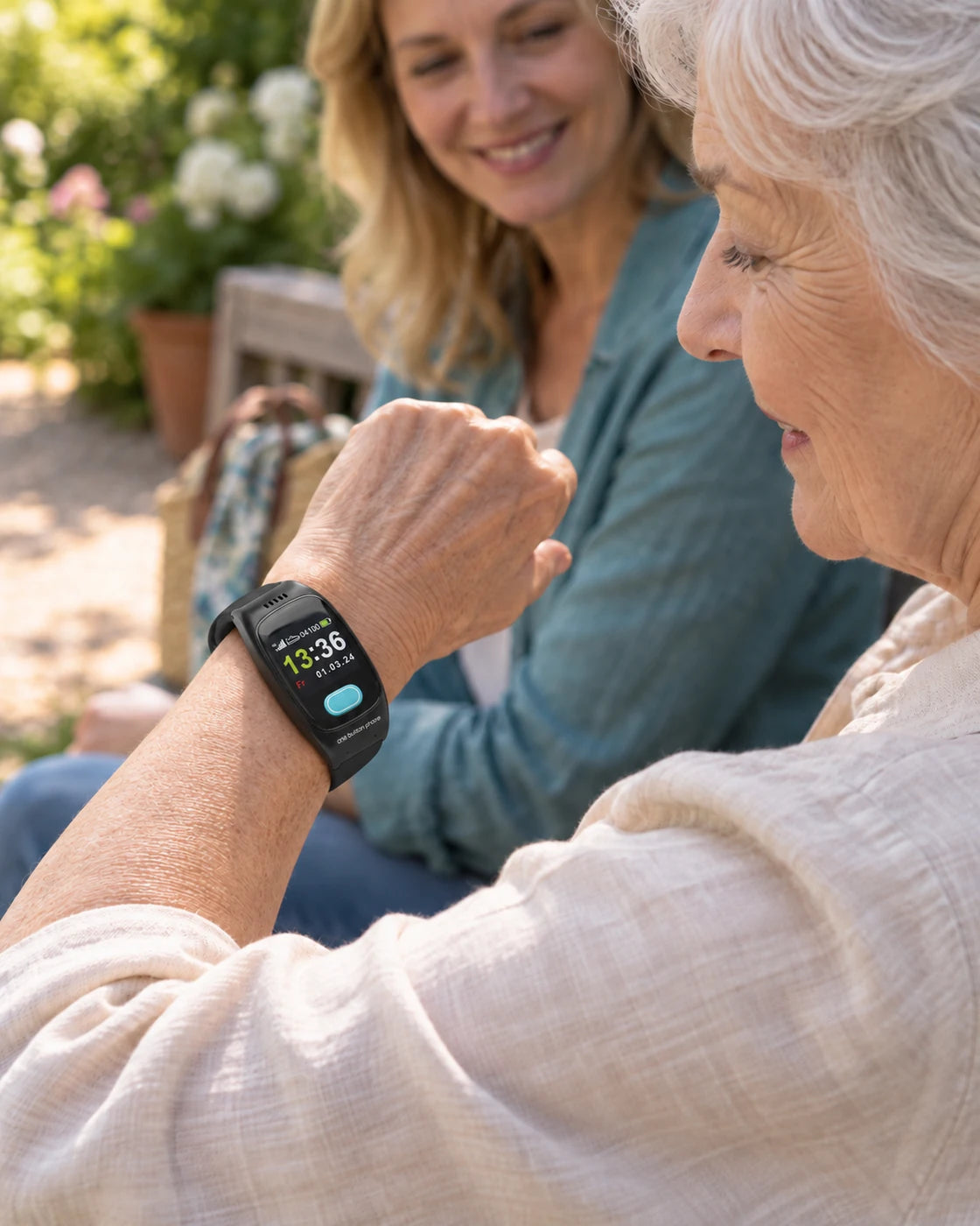 Seniorin mit One Button Phone am Handgelenk und ihrer Tochter im Garten